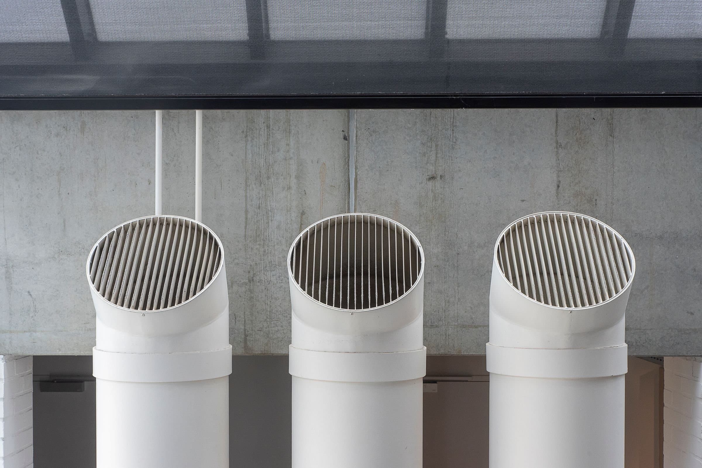 Three ventilation intakes against a concrete wall.