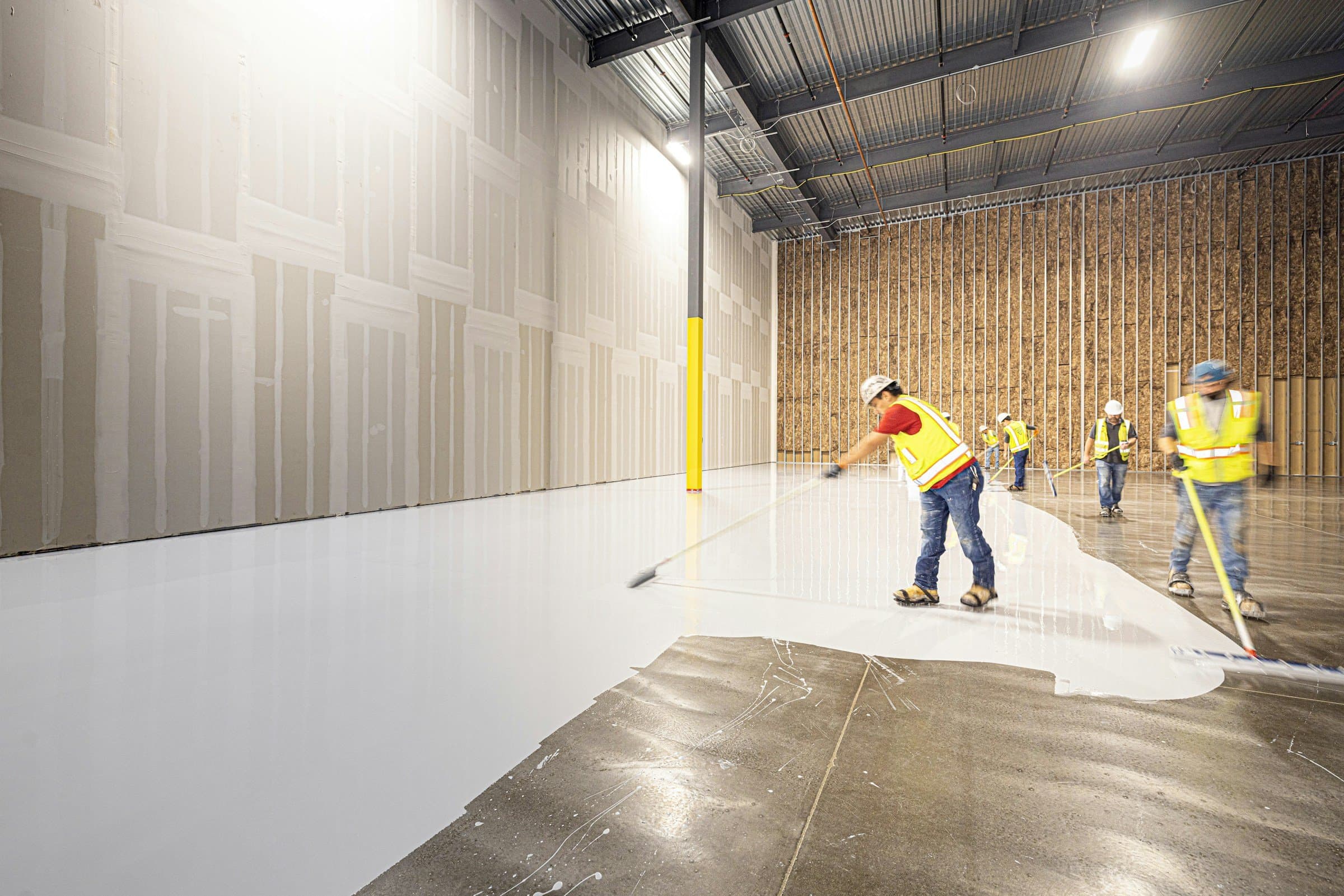 A crew coats the concrete floor of a new warehouse.