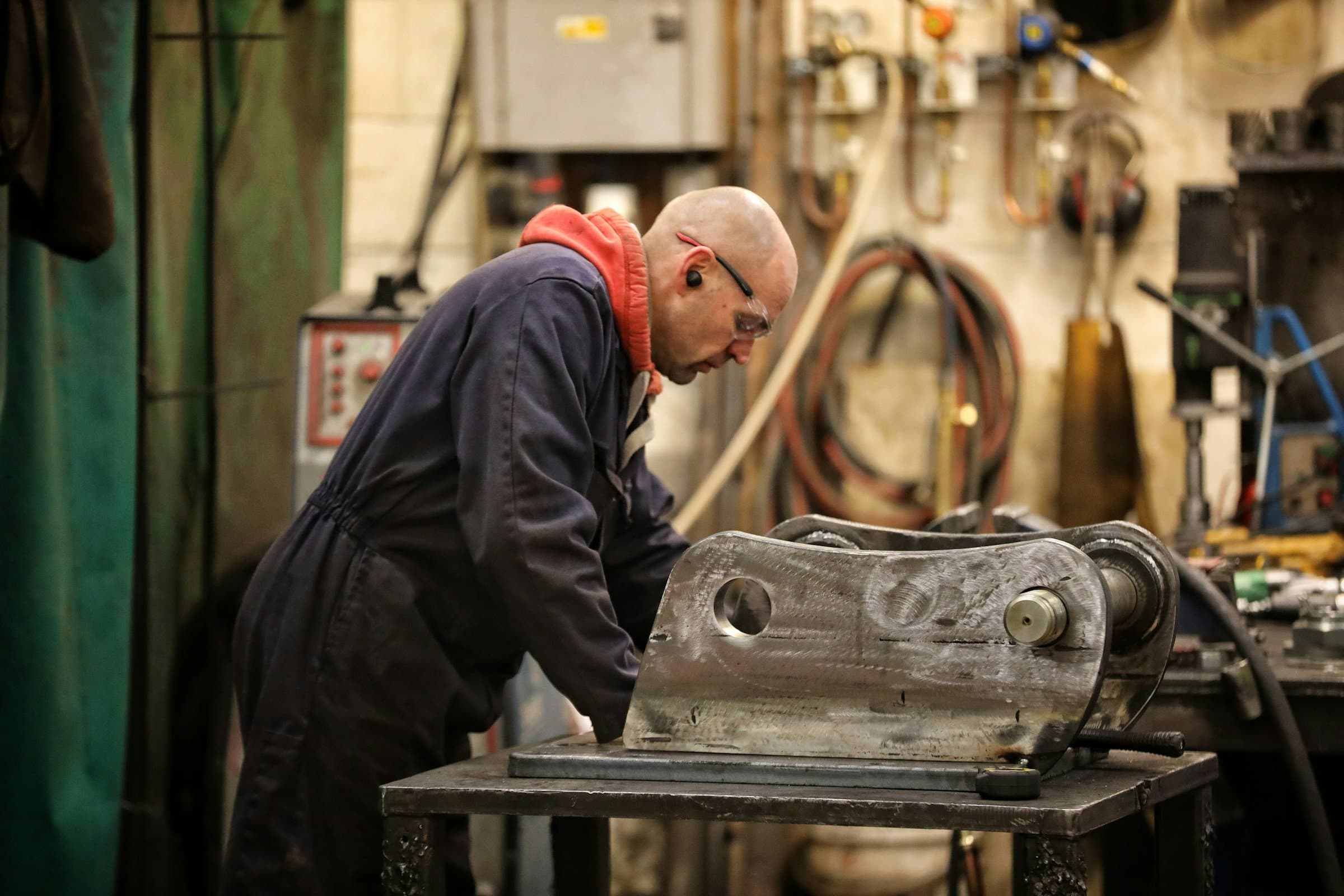 A fabricator works a heavy steel part in a machine shop.