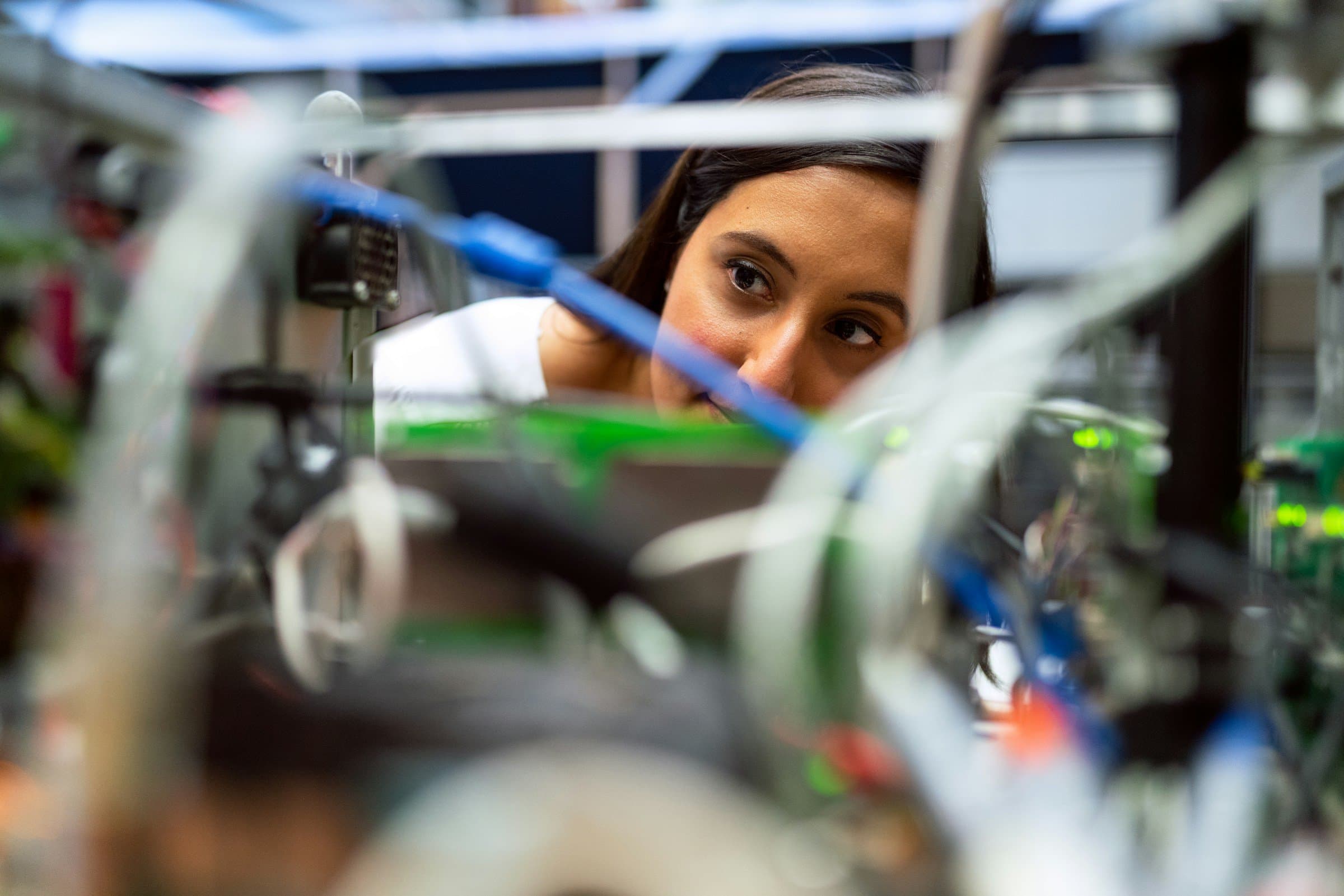 An engineer inspects prototype hardware through a tangle of wiring.